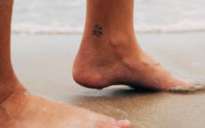 persons feet on white sand during daytime