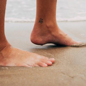 persons feet on white sand during daytime